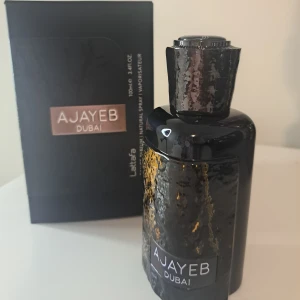 Ajayeb Dubai parfym från Lattafa - Ajayeb Dubai från Lattafa är en parfym med söt, varm och kryddig doftprofil, inslag av kaffe, trä, vanilj och karamell. Flaskan är svart med guldiga detaljer och har en unik, texturerad yta. Rymmer 100 ml och passar både kvinnor och män. Oanvänt. 100% ny 
