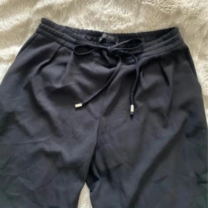 Svarta mjukisbyxor från Zara Basic - Svarta mjukisbyxor från Zara Basic med elastisk midja och snörning framtill. Byxorna har raka ben, diskreta bakfickor och är gjorda i ett mjukt material som känns skönt mot huden. Perfekta för en chill och avslappnad stil.