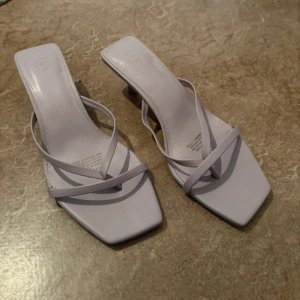 Ljuslila sandaler med smala remmar H&M - Trendiga ljuslila sandaler från H&M med smala remmar och fyrkantig tå. Skorna har låg klack och öppen tå, perfekt för en stilren look. Tillverkade i syntetmaterial och passar dig som gillar minimalistisk design.
