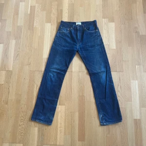 Levi's 505 Special Edition jeans  - Klassiska Levi's 505 Special Edition jeans i mörkblå denim. Rak passform med fem fickor och orange kontrastsömmar. Tidlös modell med vintagekänsla, tillverkad i slitstarkt bomullsjeans. Perfekta för dig som gillar retrostil och vill ha ett par snygga jeans med ikonisk look. 31/32