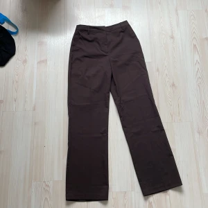 Bruna raka byxor från BikBok - Snygga bruna byxor från BikBok i rak modell. De har hällor för bälte och är tillverkade i ett mjukt bomullstyg. Perfekta för en clean och stilren look. Passar dig som gillar klassiska och enkla byxor med lite loose fit.