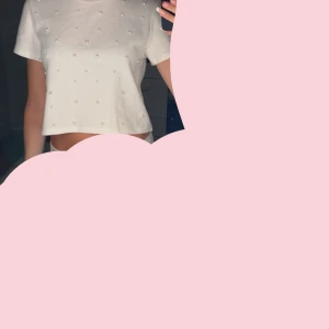 Vit croppad topp med pärlor - Superfin vit croppad topp med korta ärmar och pärldetaljer över hela framsidan. Perfekt för dig som vill ha en söt och stilren look med lite extra bling. Enkel att matcha med både jeans och kjol.