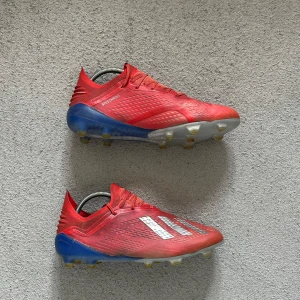 Adidas X 18.1 FG/AG - Snygga röda Adidas X 18.1. Ovandelen är i syntetmaterial med texturen Speedmesh och snörning för bra passform. Perfekta för dig som vill sticka ut på planen. (Säljer av massa skor nu pga flytt och jag inte kan ta med allt)