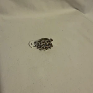 Silvrig ring med nitar, storlek 6 - Cool och edgy silvrig ring med flera små konformade nitar runt hela ovansidan. Ringen har en bred design och ger en riktigt tuff vibe, perfekt för dig som gillar statement-smycken. Metallfinishen är blank och drar blickarna till sig.