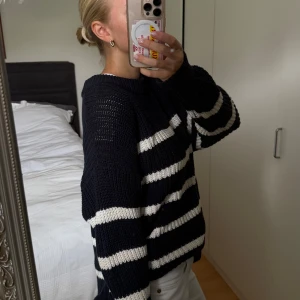 Randig stickad tröja i marinblått och vitt - Säljer en mysig stickad tröja i marinblått med vita ränder. Tröjan har en avslappnad passform och långa ärmar, perfekt för kyligare dagar. Den är både stilren och bekväm, ett måste i garderoben! Den är i storlek L som ger en oversized look på mig som bär storlek S.
