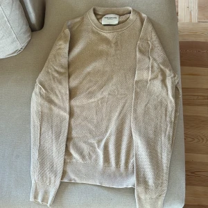 Beige stickad tröja These Glory Days - Säljer en beige stickad tröja från These Glory Days. Tröjan har rund halsringning, lång ärm och ribbade muddar. Perfekt för lager-på-lager och enkel att matcha med jeans eller chinos.