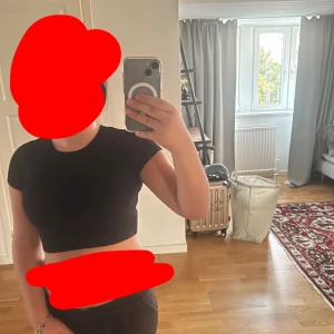 Svart croppad topp med kort ärm - Enkel och stilren svart croppad topp med korta ärmar. Sitter tight och har en klassisk rund halsringning. Perfekt att matcha med höga jeans eller kjol för en clean look. Den är i storlek  S, ifrån Zara.