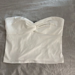 Vit bandeau tubtopp från BikBok strl XL - Snygg vit bandeau tubtopp från BikBok i storlek XL. Toppen har twistad detalj framtill och smockad baksida för extra komfort. Gjord i mjukt, stretchigt material som sitter skönt och passar perfekt till varma dagar.