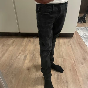 Replay Anbass Hyperflex svarta jeans - Säljer ett par Replay Anbass Hyperflex jeans i svart tvättad denim. Jeansen har en slim passform, klassiska fem fickor och snygga detaljer på bakfickorna. Stretchigt material som gör dem riktigt bekväma och perfekta för en modern look.