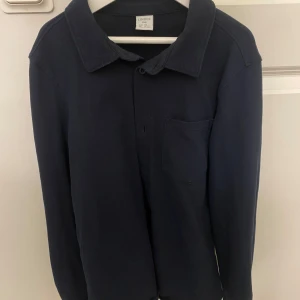 Mörkblå skjorta från Lindex Kids - En stilren mörkblå skjorta från Lindex i storlek 146. Skjortan har klassisk krage, bröstficka och långa ärmar. Skjorta/overshirt.