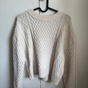 Beige stickad tröja med flätmönster från H&M - Säljer en beige stickad tröja med snyggt flätmönster från H&M. Tröjan har rund halsringning och ribbade muddar vid ärmslut och nederkant. Användes ett antal gånger, men är i mycket bra skick. 