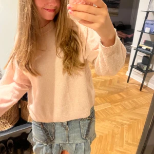 Ljusrosa stickad tröja - Supermjuk ljusrosa stickad tröja med rund hals och långa ärmar. Tröjan har en relaxed passform och ribbade muddar vid ärmslut och nederkant. Perfekt att slänga på sig för en chill och snygg look.