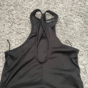 Svart ribbad linnetopp FB Sister - Svart ribbad linnetopp från FB Sister i storlek S. Toppen har en sportig racerback och är ärmlös, perfekt för en chill och stilren look. Materialet är stretchigt och följsamt, vilket gör den superbekväm att bära.