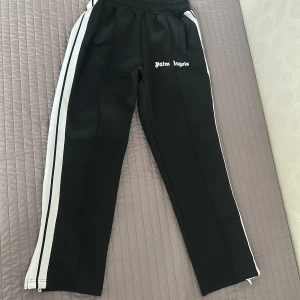 Palm Angels svarta trackpants M - Svarta trackpants från Palm Angels med vita sidoränder och logga framtill. Byxorna är knappast använda kommer med tags och påse och priset kan självklart diskuteras🏷️