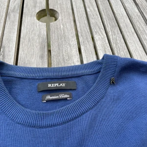 Blå bomullströja från Replay - Snygg marinblå tröja från Replay i mjuk bomull. Klassisk rund halsringning och långa ärmar med ribbade muddar. Perfekt basic-plagg med diskret Replay-logga vid halsen. Passar dig som gillar stilren och enkel look.