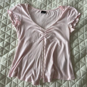 Ljusrosa topp med slitts vid magen Gina Tricot - Supersöt ljusrosa topp från Gina Tricot med v-ringning, öppning framtill och volangdetaljer på ärmarna. Kortärmad och i mjuk bomull. Pris går att diskutera☺️