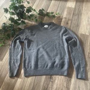 Grå stickad tröja These Glory Days - Snygg grå stickad tröja från These Glory Days. Klassisk rund halsringning och ribbade muddar vid ärmslut och nederkant. Perfekt för lager-på-lager och enkel att matcha med jeans eller chinos.