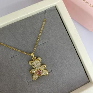 Guldigt halsband med nalle och hjärta - Supergulligt halsband med en gnistrande nallebjörn i guldton, täckt av små glittrande stenar och ett rosa hjärta på magen. Kedjan är tunn och elegant. Ej använd utan kommer från min small business. 
