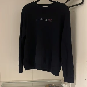 Marinblå sweatshirt från moncler  - Säljer denna Marinblå sweatshirt från Moncler, i princip nyskick marinblå sweatshirt från Moncler, klassisk modell med diskret logga på ärmen. Mycket sparsamt använd, inga defekter, fläckar eller tvättslitage – i princip nyskick. Originalköpt av mig i butik, äkta (kvitto finns). 