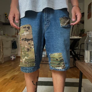 Blå jeansshorts med camo-patch - Sashiko stitch-inspired  denim shorts. Missing the front left pocket. 