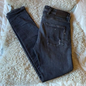 Replay Anbass Jeans - Säljer dessa galet snygga svarta/mörkgrå jeans från Replay i modell Anbass med klassisk femficksdesign och diskreta slitningar. Jeansen är från ”Aged 5 Years” kollektionen och är kända för sin unika tvätt. De har en slim passform och raka ben, perfekt för en stilren look. Mjukt denimtyg med stretch för extra komfort. Jeansen är i princip helt nya och tagsen innuti är fortfarande krit vita, de befinner sig i skick 9.5/10. Tveka inte på att höra av dig vid frågor eller funderingar! ⭐️