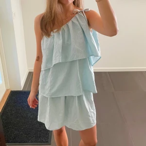 Ljusblå axelbandslös volangklänning - Supersöt ljusblå axelbandslös/oneshoulder klänning med volangdetaljer. Finns ej någon lapp men skulle säga att den passar M! 🩵