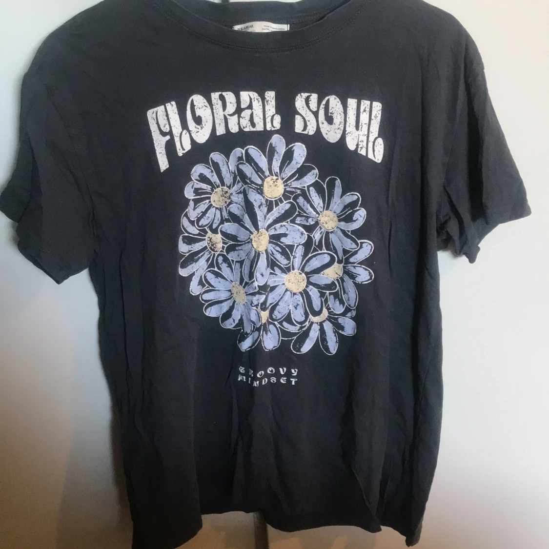 Svart t-shirt med blommigt tryck och texten 'Floral Soul'