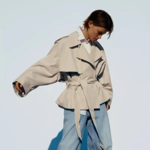 Beige trenchcoat med bälte - Säljer den eftertraktade jackan från Zara. Snygg beige trenchcoat med bred krage och knytbälte i midjan. Jackan har oversized passform. 
