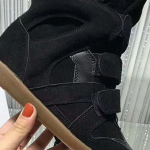 Svarta kilklack sneakers med kardborreband - Snygga svarta sneakers med kilklack och kardborreband. Skorna har en mjuk mockaliknande yta och detaljer i svart syntet. Yttersulan är i gummi och har en beige färg. Perfekta för dig som vill ha lite extra höjd men ändå vara bekväm.