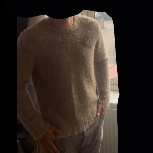 Beige/ljusbrun fluffig tröja med hjärtdetalj  - En skön långärmad tröja från StreetSpirit. Tröjan har en unik hjärtdetalj i brunt på bröstet och är perfekt för dig som gillar  trendiga plagg mot våren. ☀️ 🍁  10/10 skick, köpt för 999kr