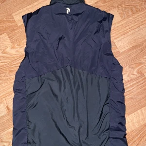 Svart väst från Peak Performance - Säljer en svart väst från Peak Performance med dragkedja framtill och två fickor med dragkedja. Västen har en hög krage och är perfekt för lager-på-lager under kyliga dagar. 