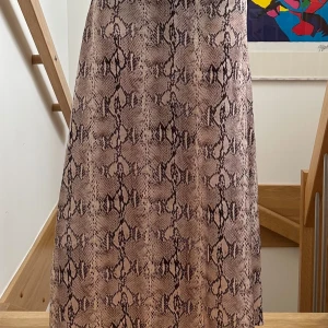 Långkjol med ormmönster - Säljer en beige långkljol med trendigt ormmönster. Kjolen har en rak och luftig passform och är perfekt för sommaren!