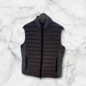 Svart dunväst från Colmar - Tja. Säljer en snygg svart dunväst från Colmar med quiltad design och hög krage. Västen har två fickor med dragkedja framtill och en diskret logotyp på bröstet. Perfekt för lager-på-lager och passar till många olika stilar.Tveka inte att höra av dig vid funderingar ✌🏻🙌🤗