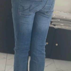 Blå bootcut jeans med broderad bakficka - Snygga blå jeans med bootcut passform och broderad detalj på bakfickan. Klassisk femficksmodell med normal passning och lätt utsvängda ben. Perfekta för en  trendig look.