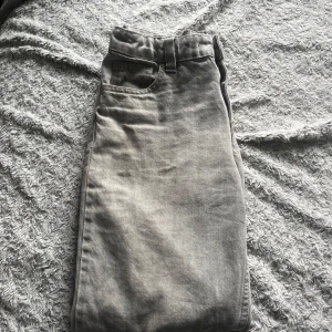 Grå jeansbyxor med rak passform - Säljer ett par grå jeansbyxor med klassisk femficksdesign och rak passform. Byxorna har normal midja och stängs med dragkedja och knapp. Perfekta till vardags för en avslappnad stil.
