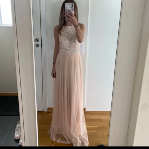 Ljusrosa långklänning med paljettliv - Säljer en elegant ljusrosa långklänning med glittrigt paljettliv och rund halsringning. Kjolen är i ett tunt, flowy material som ger en fin siluett. Perfekt för bal eller fest! Klänningen är ärmlös