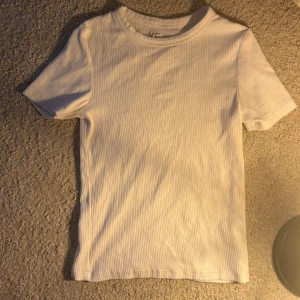 Vit ribbad t-shirt från FSBN Sister - Säljer en enkel och stilren vit ribbad t-shirt från FSBN Sister. T-shirten har korta ärmar och rund halsringning, perfekt för en clean och fräsch look. Passar till allt och är superbekväm!