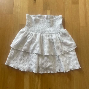 Vit volangkjol från Gina Tricot - Supersöt vit kjol från Gina Young med smock upptill och dubbla volanger. Storleken står inte kvar men den är 152.