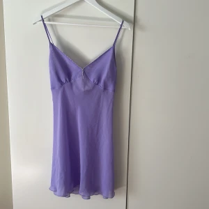 Ljuslila axelbandslös klänning slip dress vintage - Helt otroligt vintage slip dress med pärlor längs bysten. Köpt från UK. Säljer en söt ljuslila klänning med tunna axelband och lätt v-ringning. Klänningen är kort och har ett luftigt, flowy tyg som ger en romantisk känsla. Perfekt för varma dagar eller sommarens fester.