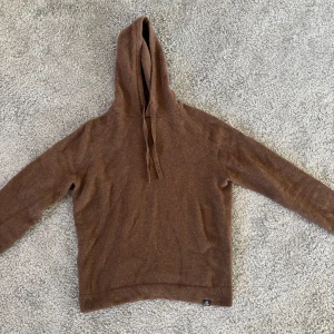 Brun hoodie i ull från Marc O'Polo - Säljer en brun hoodie från Marc O'Polo i mjuk och ansvarsfullt producerad ull. Tröjan har långa ärmar, huva med dragsko och en enkel, stilren design. Perfekt för dig som gillar klassiska och bekväma plagg. Hör av dig vid frågor! 