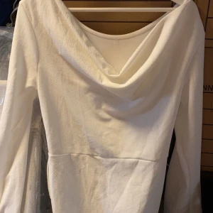 Vit långärmad klänning med draperad hals - Säljer en elegant vit klänning med lång ärm och snyggt draperad v-ringad hals. Perfekt för dig som vill ha en stilren look med lite extra detalj upptill.