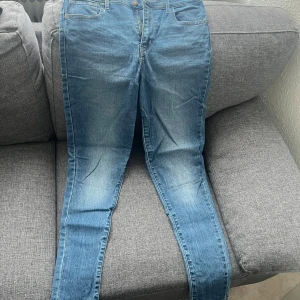 Blå skinny jeans från Levi's - Säljer ett par klassiska blå skinny jeans från Levi's med fem fickor och knappgylf. Jeansen har en snygg tvätt och passar perfekt till vardagslooken. Levi's-logga syns på bakfickan.