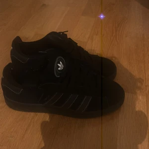 Svarta Adidas Campus 00 - Säljer ett par svarta Adidas campus 00. Jag jag änvänt dem 2 gånger i en väldigt kort period. Riktigt bra skick. Hör av er för mer information 😀