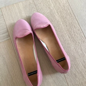 Rosa ballerinaskor från Vagabond - Säljer ett par klassiska rosa ballerinaskor från Vagabond. Skorna har rund tå och är tillverkade i ett mjukt material med en enkel och stilren design. Perfekta för dig som gillar en feminin och bekväm stil.