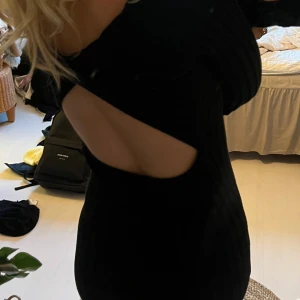 Svart ribbad långklänning med öppen rygg - Säljer en svart ribbad långklänning med lång ärm och snygg öppen rygg. Klänningen har en tight passform med vida ärmar och slutar strax vid mitten av smalbenet på mig som är 167cm lång🩵🩵