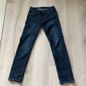Mörkblå jeans från Lee - Snygga mörkblå jeans från Lee med klassisk femficksdesign och raka ben. Jeansen har gul kontrastsöm och är tillverkade i slitstarkt denimtyg. Perfekta för dig som gillar en tidlös och clean look.