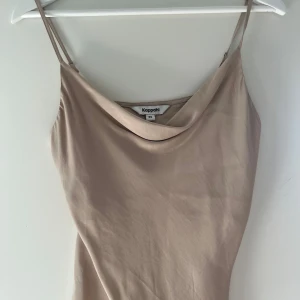 Beige satin linne från Kappahl - Supersnyggt beige linne från Kappahl i satin med tunna axelband och draperad halsringning. Linnet har en mjuk, glansig yta.💛