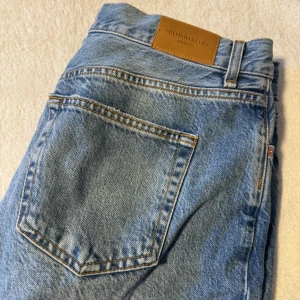 Ljusblå raka jeans från Gina Tricot - Ljusblå jeans från Gina Tricot med raka ben. Jeansen har hög midja, kontrastsömmar och en läderpatch bak i midjan med 'Premium Denim'. Använda någon gång. Säljer pga fel storlek. 