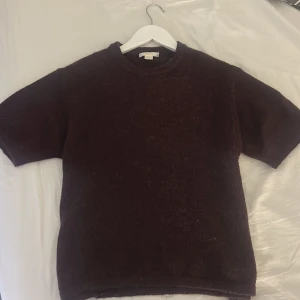 Vinröd stickad kortärmad tröja - Säljer en vinröd stickad tröja från gina med korta ärmar och rund halsringning. Tröjan har en enkel, rak passform och är gjord i ett mjukt, lite luddigt material som känns både trendigt och bekvämt.