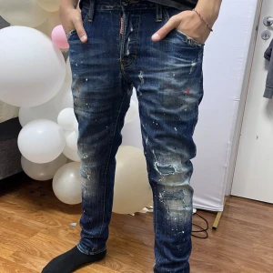 Dsquared2 blå jeans med stänk  - Säljer begagnade dsquared2 jeans. Ligger bara i garderoben så tänkte sälja. Köpta på Minto.se och är helt autentiska (Äkta). Modellen är 180cm och väger 70kg. De är även slim jeans .Vid frågor skriv! 